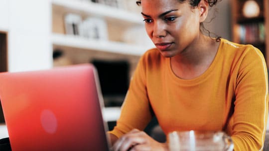 Woman looks intently at an open laptop.